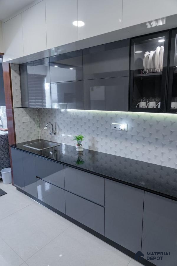 Modern kitchen with glossy grey and white laminate cabinets, black granite countertop, and 3D geometric white backsplash tile in Bengaluru | Material Depot