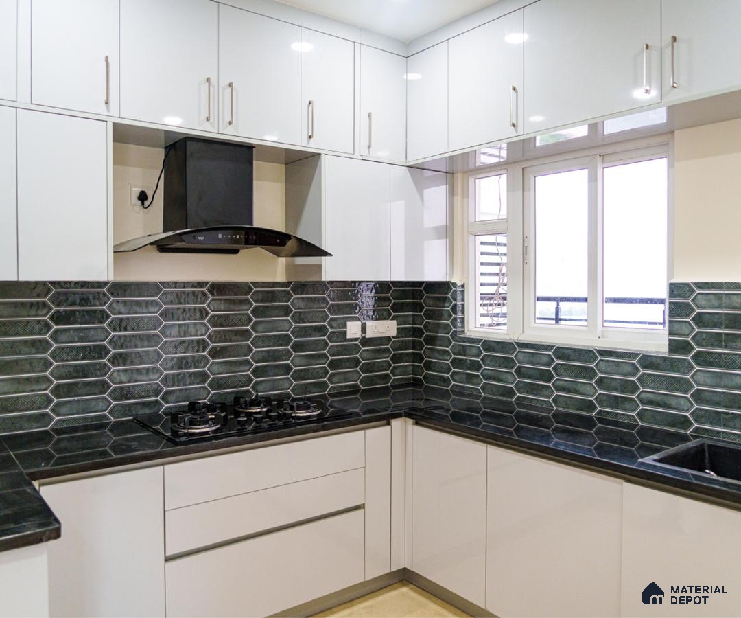 Modern kitchen with glossy white laminate cabinets, black granite countertop, and green geometric backsplash tiles in Bengaluru | Material Depot