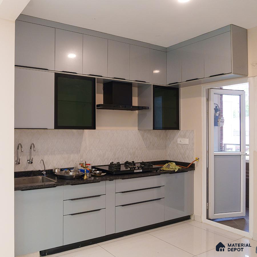 Modern kitchen with grey high gloss laminate cabinets, black granite countertop, and white geometric backsplash tile in Bengaluru | Material Depot