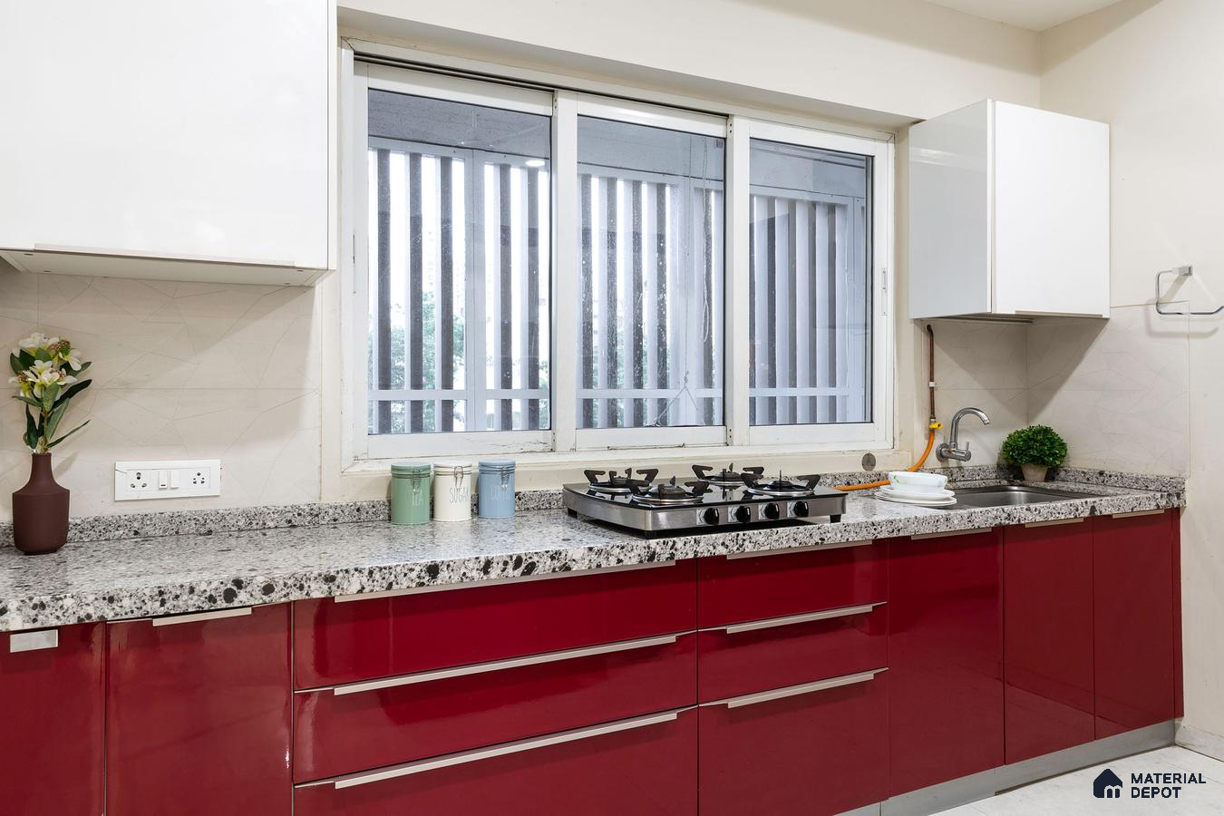 Modern kitchen with high gloss red laminate cabinets and speckled granite countertop in Bengaluru | Material Depot